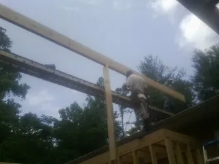 Carpenter setting a ridge beam over a new addition frame — Ice Dam Removal by Roofing Brothers in Lee Center