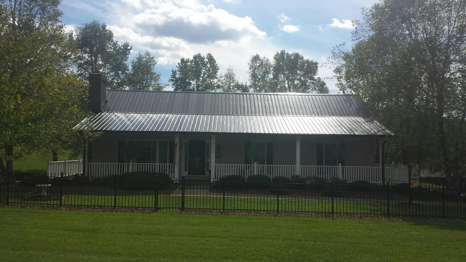 Gray metal roof on a brick ranch with a full width front porch — Gutter Guard Installation work by our crew in Lee Center