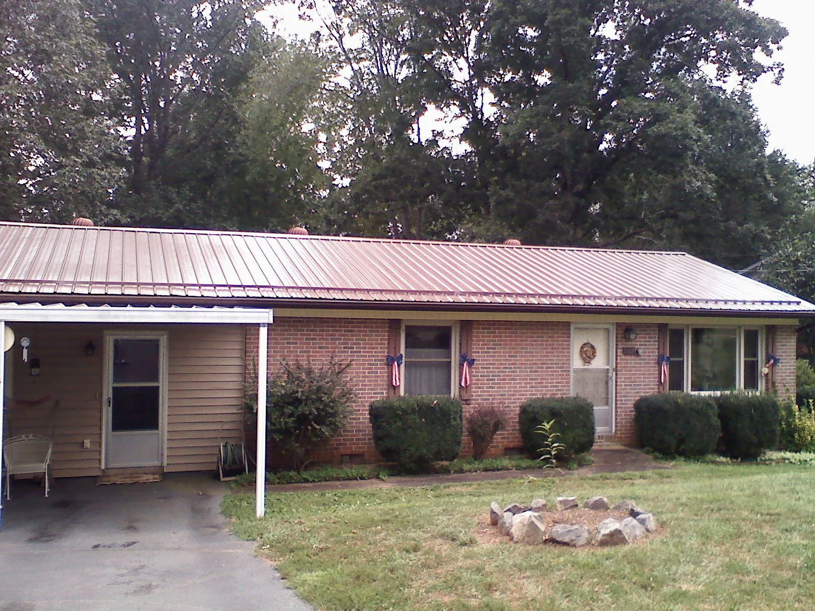 Bronze metal roof and carport on a brick ranch home — Roof Repair work by our crew in Lee Center