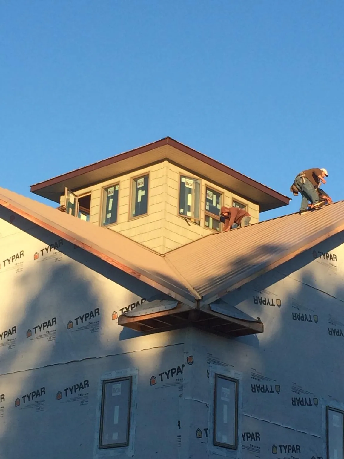 Roofers working around a rooftop cupola on a new metal roof at sunset — Roof Waterproofing in Lee Center by Roofing Brothers